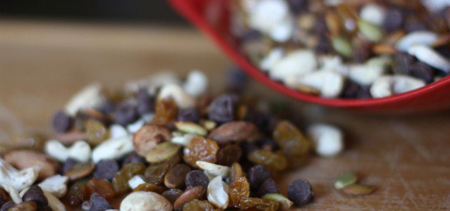 A bowl brimming with easy trail mix filled with cashews, almonds, raisins and chocolate chips.