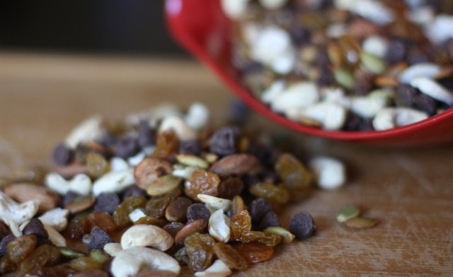 A bowl brimming with easy trail mix filled with cashews, almonds, raisins and chocolate chips.