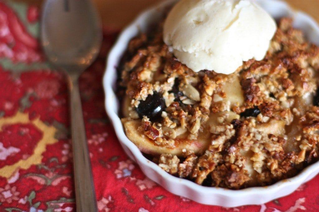 A serving of delicious apple, pear, blueberry crisp topped with vanilla coconut milk ice cream.