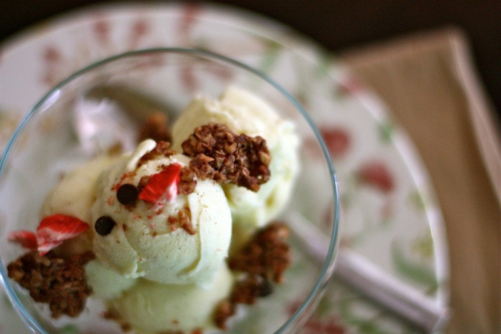 vanilla coconut ice cream topped with granola served in a glass bowl