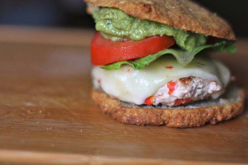 A chili lime chicken burger piled high with fresh guacamole, lettuce, tomato, homemade mayonnaise, and pepper jack cheese.