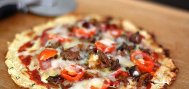 A Cheesy Cauliflower Crust Pizza topped with chorizo sausage, bacon, onions and peppers.