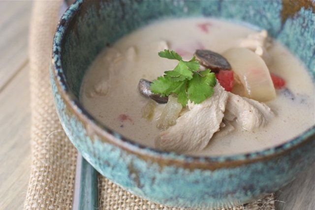 Tom Kha Gai Thai Coconut Soup sprinkled with basil in a blue decorative bowl