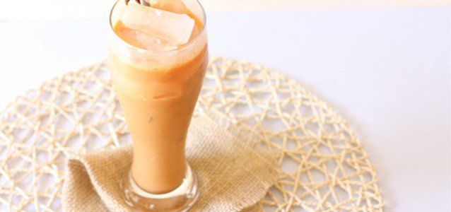 A tall glass Thai Iced Tea brimming with sweetness and creaminess.