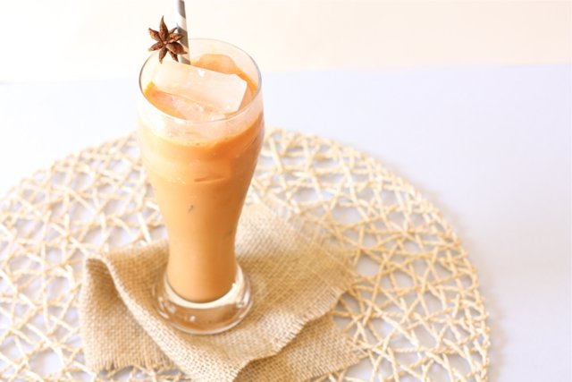 A tall glass Thai Iced Tea brimming with sweetness and creaminess.