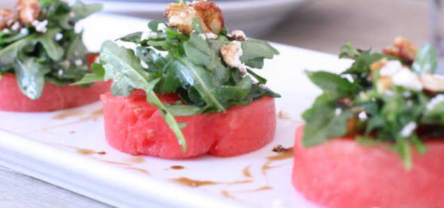 watermelon salad with arugula and goat cheese cut in circles on top of a white dish ready to be served
