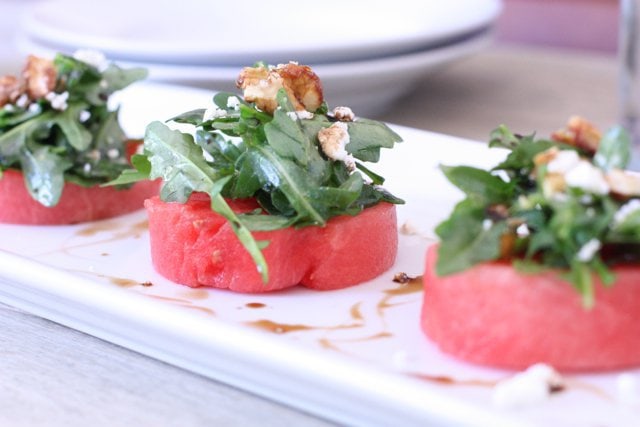 watermelon salad with arugula and goat cheese cut in circles on top of a white dish ready to be served