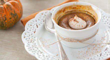 maple pumpkin custard in a bowl with whipped cream on top and a spoon next it
