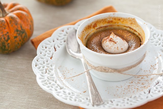 maple pumpkin custard in a bowl with whipped cream on top and a spoon next it