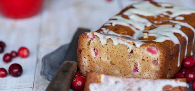 A loaf of cranberry lemon bread topped with a lemon glaze.