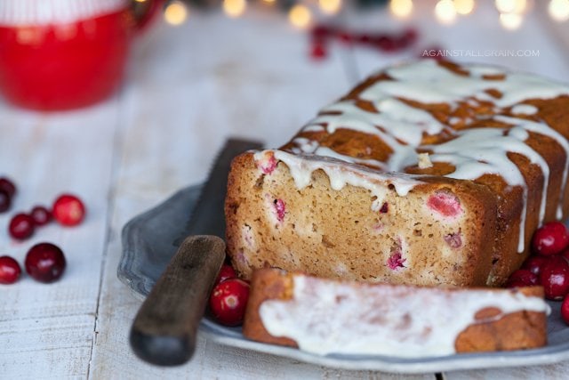 A loaf of cranberry lemon bread topped with a lemon glaze.