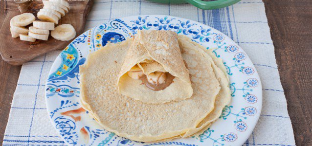 A plate of gluten free crepes filled with almond butter and bananas.