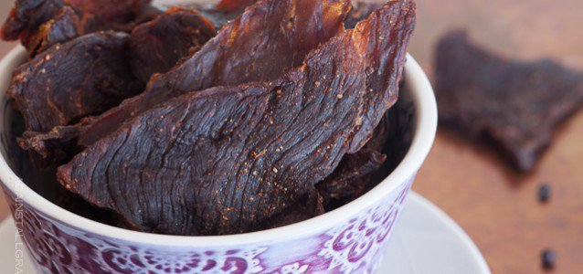 smoky healthy beef jerky sticking out of a decorative cup with some in the background half eaten