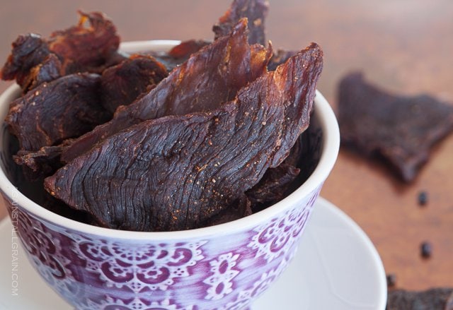 smoky healthy beef jerky sticking out of a decorative cup with some in the background half eaten