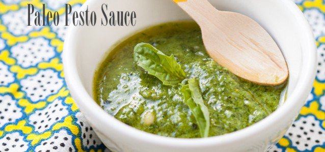dairy free pesto sauce in a bowl on a textured placemat and wooden spoon