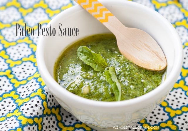 dairy free pesto sauce in a bowl on a textured placemat and wooden spoon