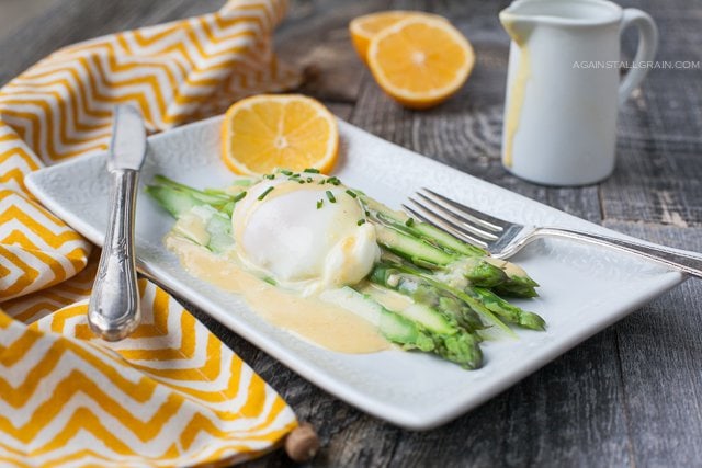 A delicious looking plate of Asparagus Benedict topped with hollandaise sauce and poached egg.