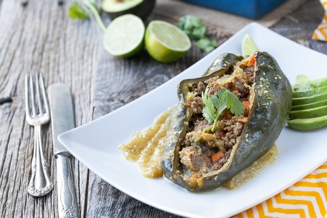 A plate of smokey pablano peppers stuffed with a mix of ground beef, sweet potatoes, carrots, and spinach seasoned with mexican seasonings and homemade tomatillo sauce.