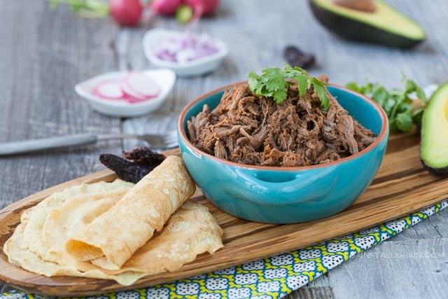 chipotle barbacoa tacos in a bowl with grain free tortillas on a cutting board next to them