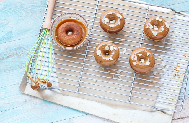 A cooling rack of cake like gluten free donuts topped with a caramel glaze.
