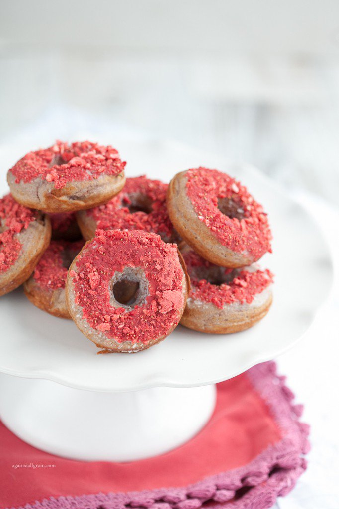 close up view of strawberry donuts neatly stacked on a white serving platter