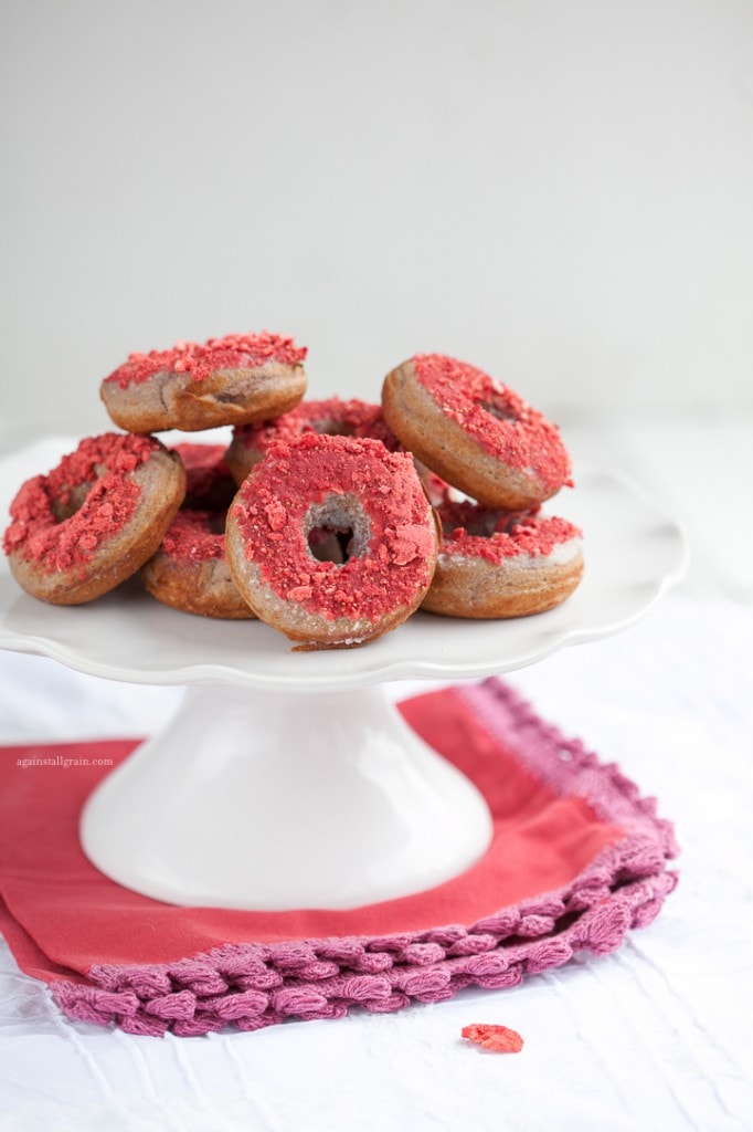 strawberry donuts neatly stacked on a white serving platter