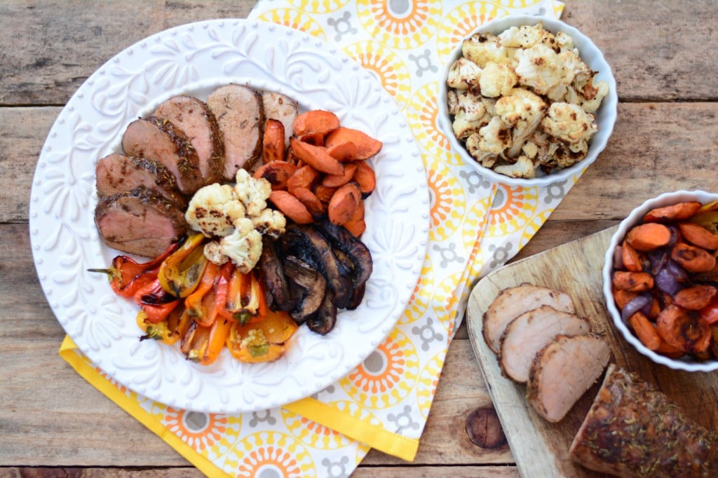 maple ternderloin served on a white plate surrounded by a variety of roasted vegetables