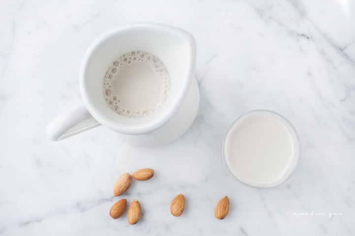 A cup and pitcher of homemade almond milk.