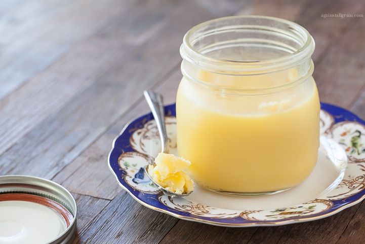 homemade ghee with a spoonful taken out and placed on a decorative plate