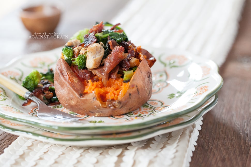 A delicious looking sweet potato stuffed with bacon, spinach, brussels sprouts, and chicken.