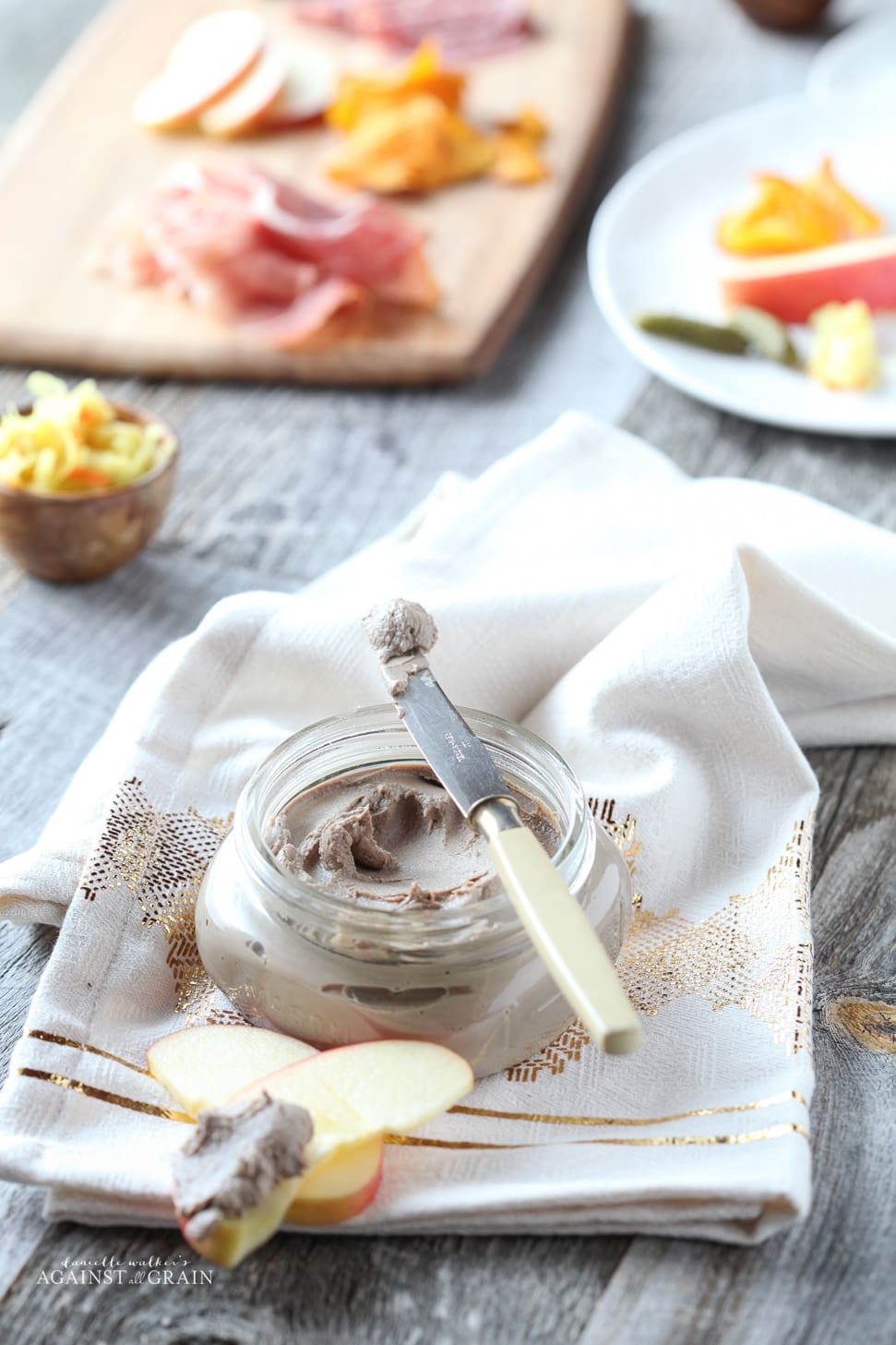 small jar of chicken liver mousse set on a napkin placed on a wooden table