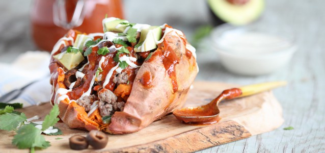 A "loaded" sweet potato topped with grass fed beef, enchilada sauce, avocado and sour cream!
