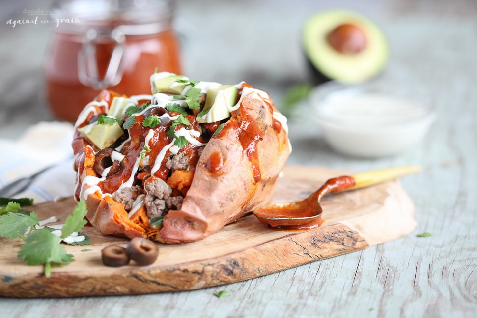 A "loaded" sweet potato topped with grass fed beef, enchilada sauce, avocado and sour cream!