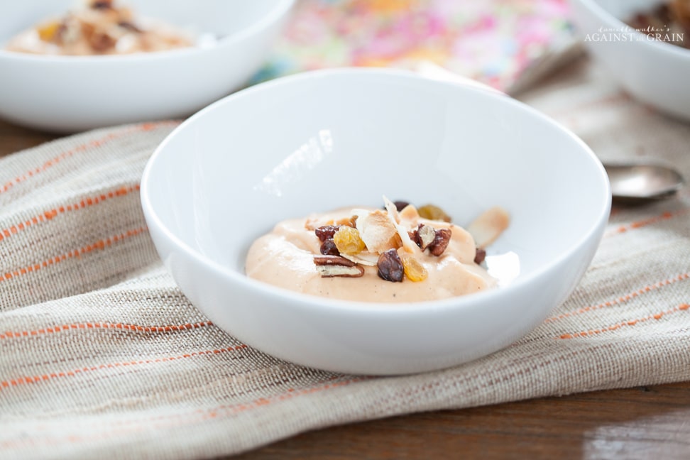 A bowl of dairy free carrot cake pudding topped with seeds and nuts.