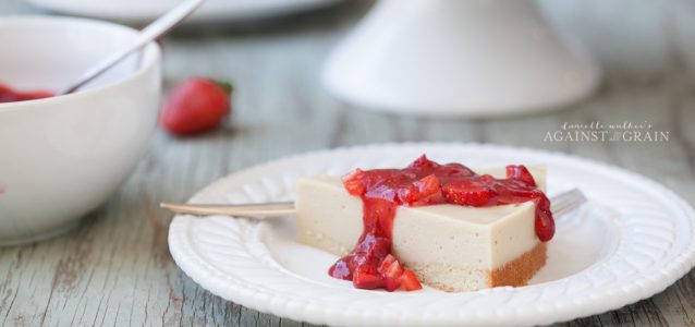 A piece of creamy cheesecake that is gluten and dairy free topped with luscious strawberry sauce.