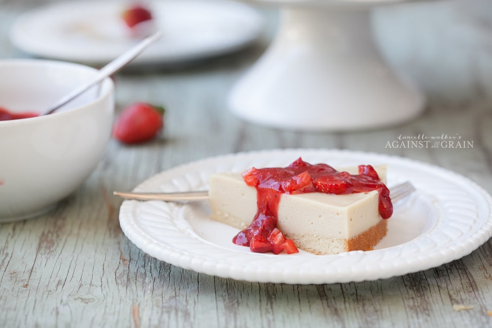 A piece of creamy cheesecake that is gluten and dairy free topped with luscious strawberry sauce.