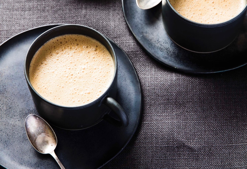 healthy pumpkin spice latte in a black mug on a saucer and spoon next to it