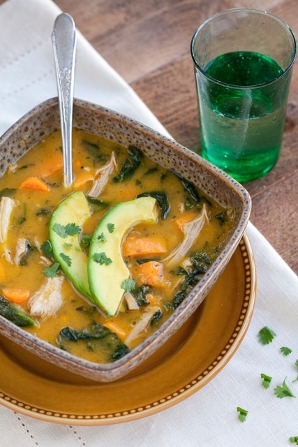 Mexican Instant Pot Chicken Soup served in a rustic brown bowl on a wooden table next to a glass of water