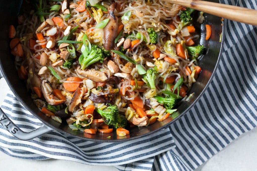 Vegetarian Sweet Chili Noodle Stir-Fry in a wok being stirred by a wooden spoon