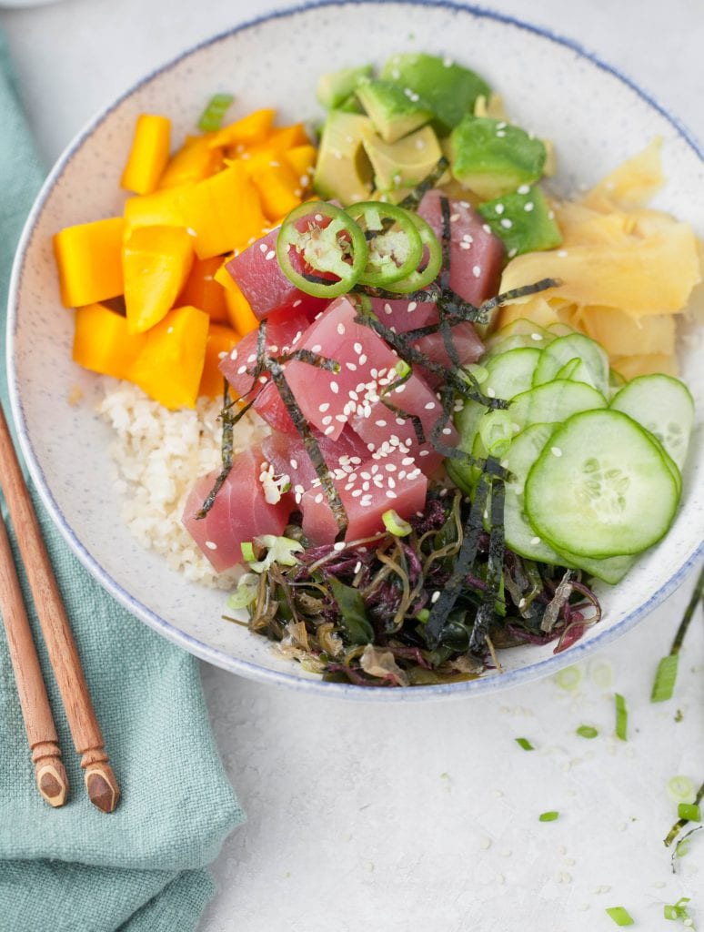 poke bowl with raw tuna, cauliflower rice, avocado, ginger, mango and thin slices of cucumber