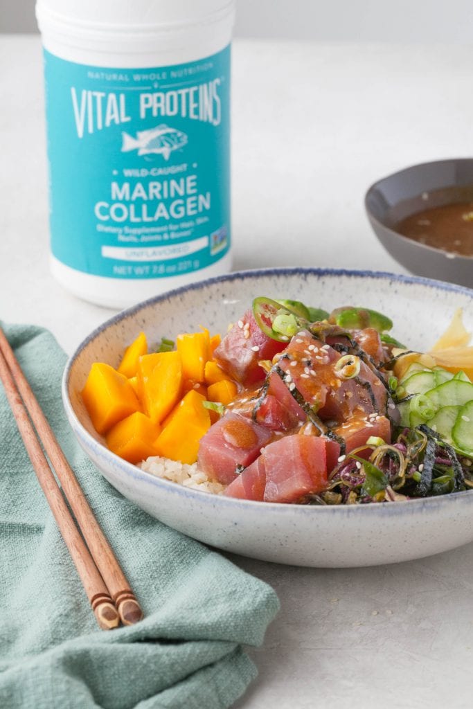 poke bowl with raw tuna, cauliflower rice, avocado, ginger, mango and thin slices of cucumber with a canister of Vital Proteins Marine Collagen in the background