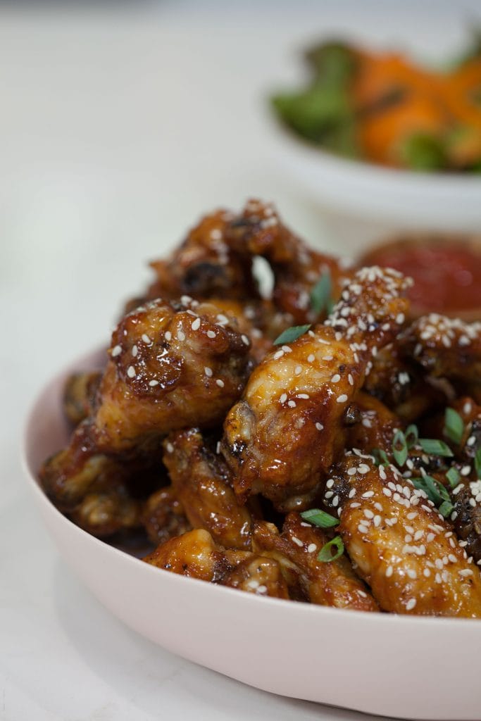 Sticky Sesame Chicken Wings in a white plate garnished with chopped scallions