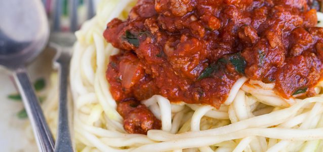 instant pot spaghetti sauce on top of squash noodles with a fork next to it