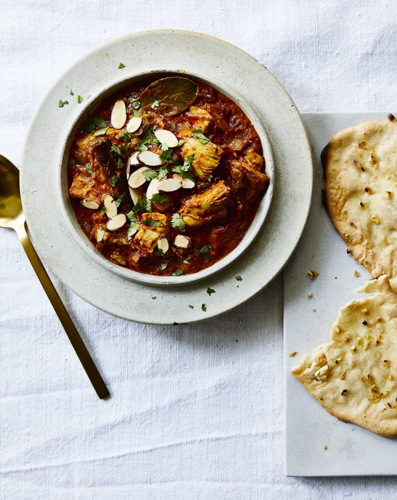 Indian Butter Chicken served in a white bowl with a side of naan