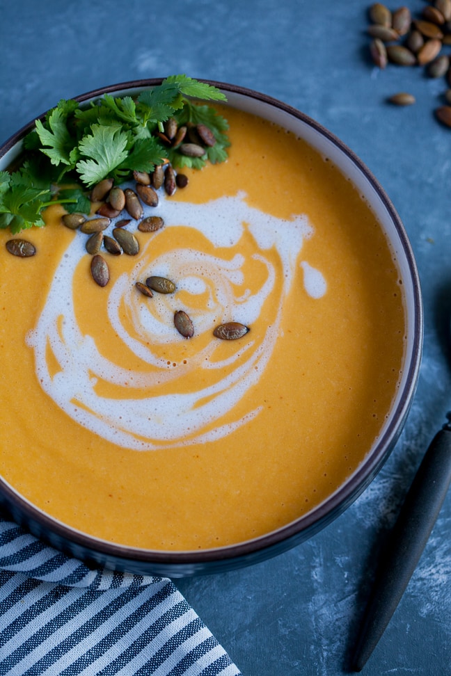 Red Curry Butternut Squash Soup in a black bowl garnished with roasted pipits and cilantro