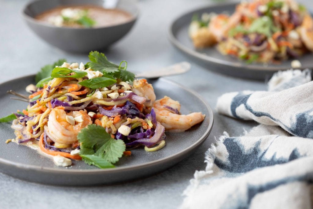 gluten free pad Thai on a gray plate with a napkin next to it