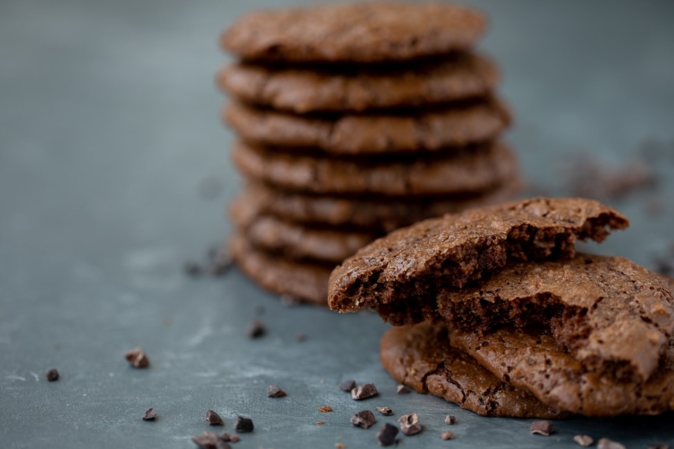 gluten free brownie corner cookies on a table stacked up seven high with several cookies in foreground half eaten