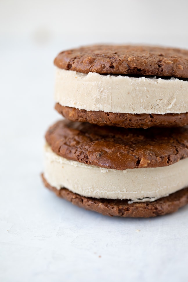 brownie cookies with a coffee ice cream middle stacked on top of each other on a white counter