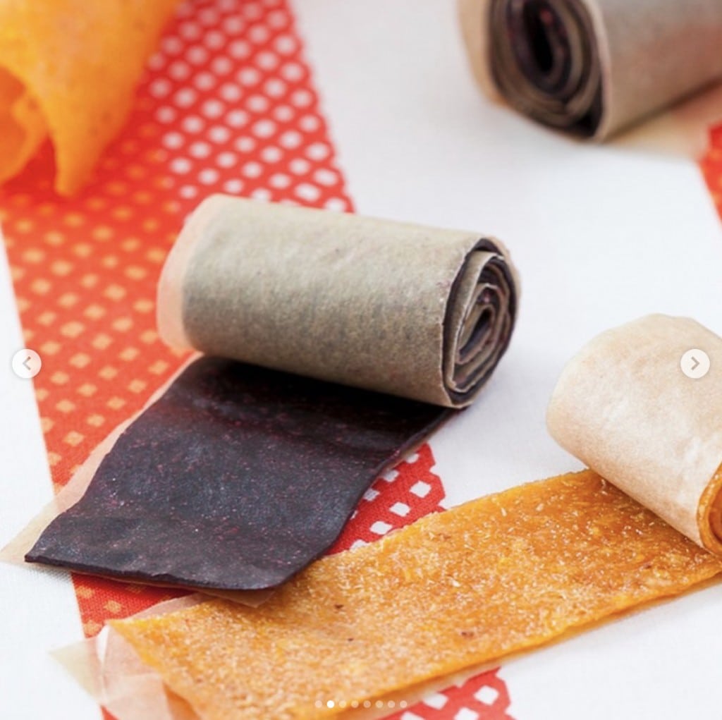 Purple and orange fruit roll ups displayed on a white and red surface 