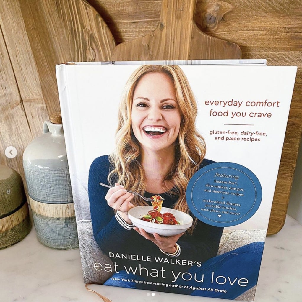 shot of Eat What You Love cookbook standing upright - book cover features Danielle Walker smiling at the camera while eating a bowl of pasta